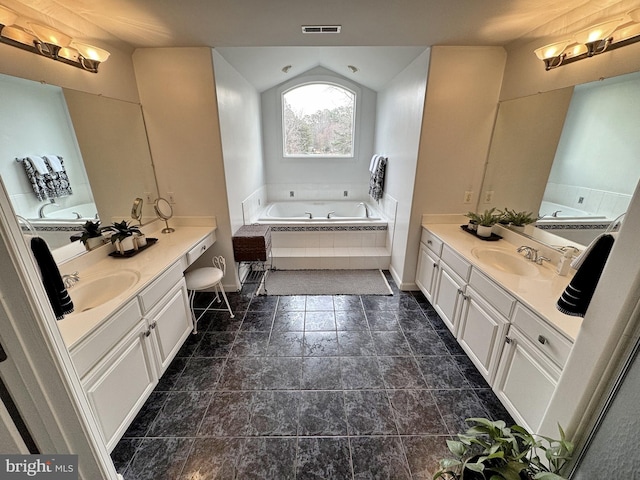 bathroom with vanity, tiled tub, and lofted ceiling