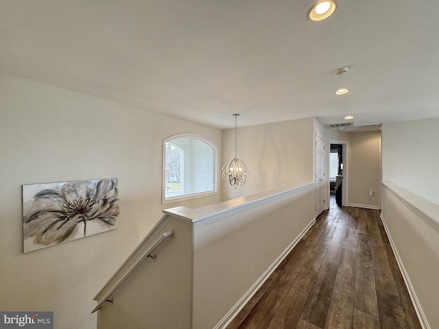 corridor featuring dark wood-type flooring and a chandelier