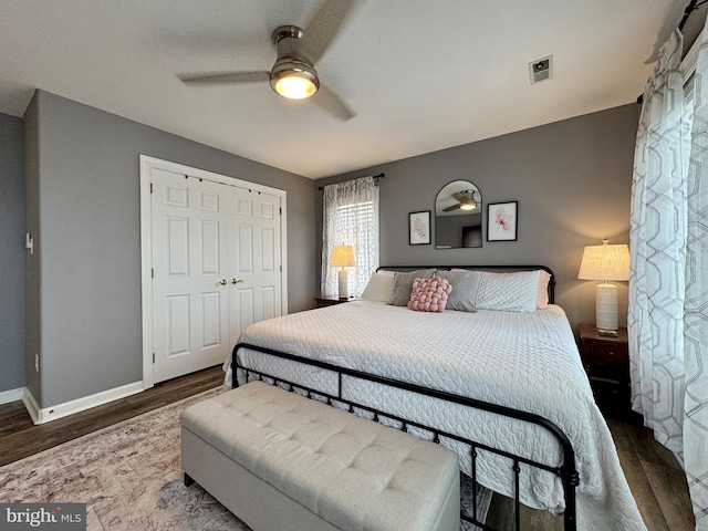 bedroom with dark wood-type flooring, ceiling fan, and a closet