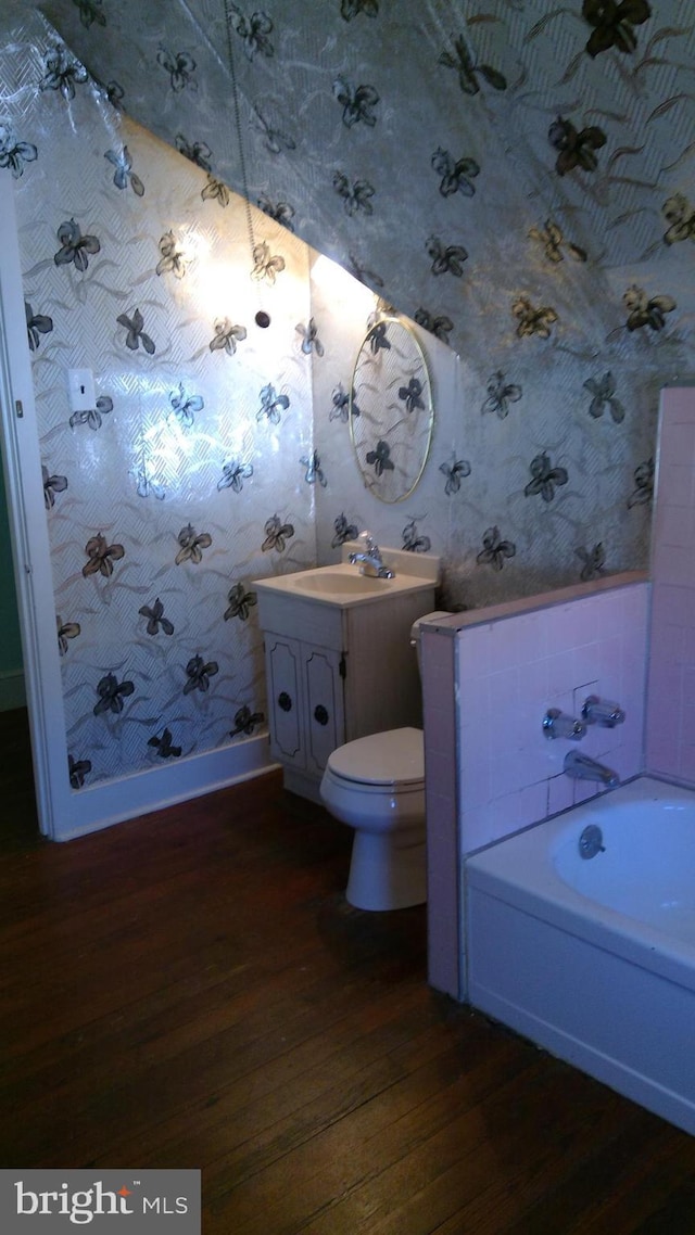 bathroom with vanity, hardwood / wood-style floors, a tub, and toilet