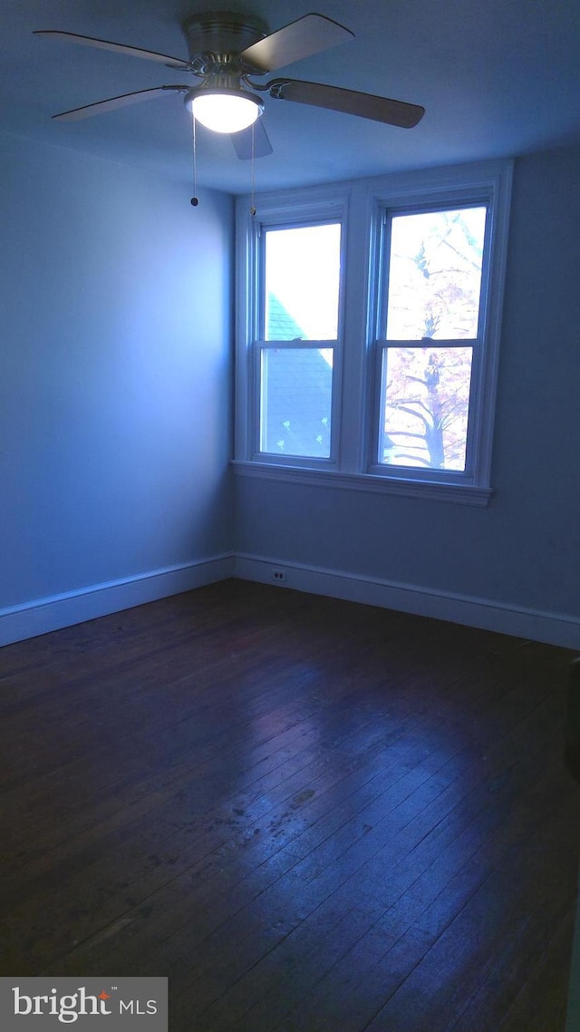 empty room featuring ceiling fan, plenty of natural light, and dark hardwood / wood-style flooring