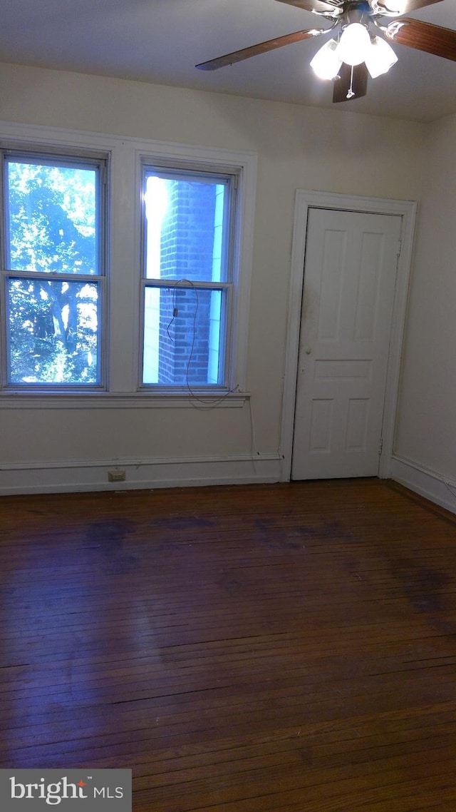 empty room with ceiling fan and dark hardwood / wood-style flooring