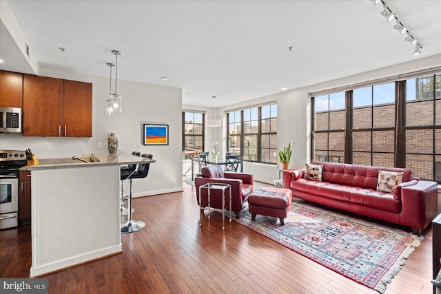 living room featuring visible vents, rail lighting, baseboards, and dark wood-style flooring