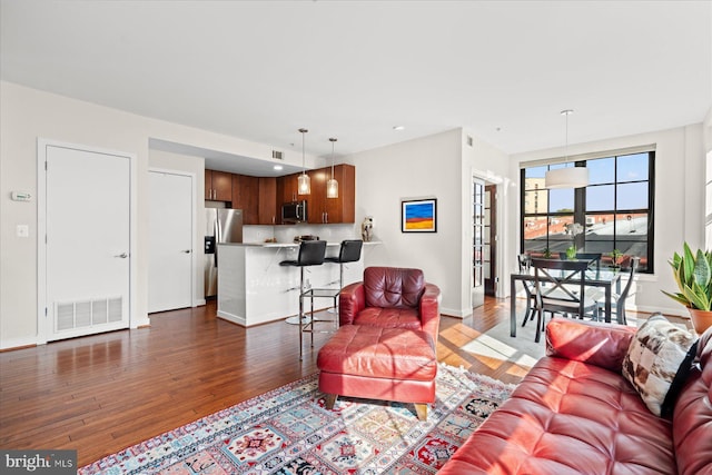 living room with recessed lighting, wood finished floors, visible vents, and baseboards