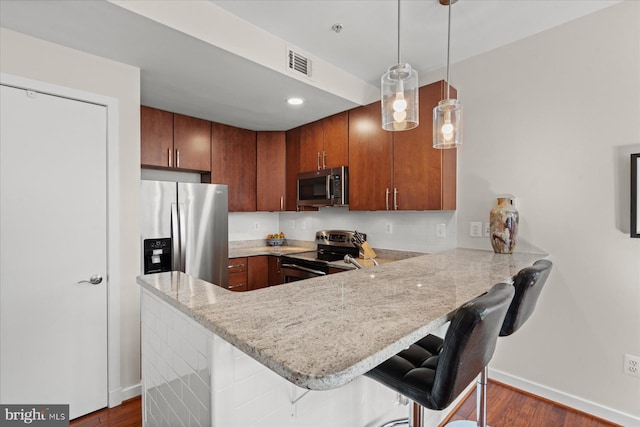 kitchen featuring visible vents, a kitchen breakfast bar, stainless steel appliances, a peninsula, and baseboards