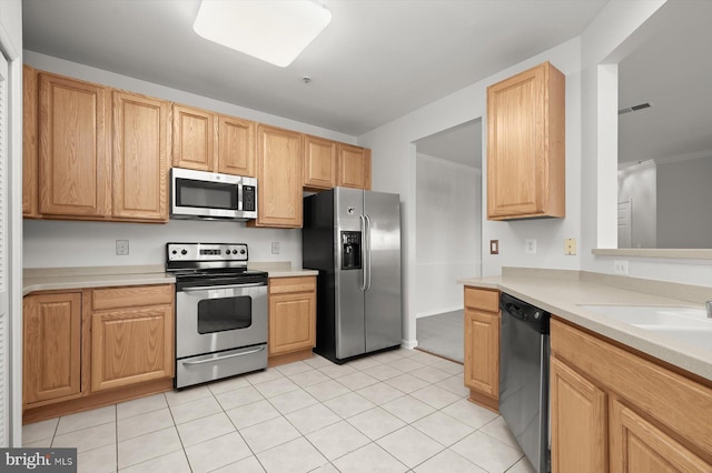 kitchen with light brown cabinetry, light tile patterned floors, crown molding, and appliances with stainless steel finishes