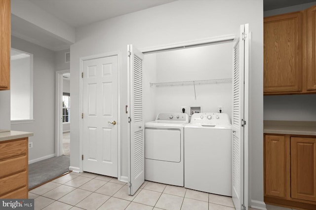 clothes washing area with light tile patterned floors and washer and clothes dryer