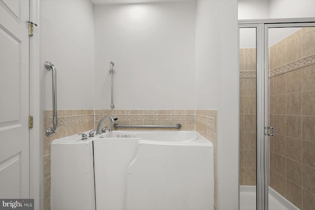 bathroom with separate shower and tub and tile walls