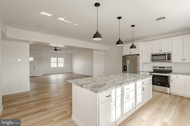 kitchen with stainless steel appliances, white cabinetry, a center island, and decorative light fixtures