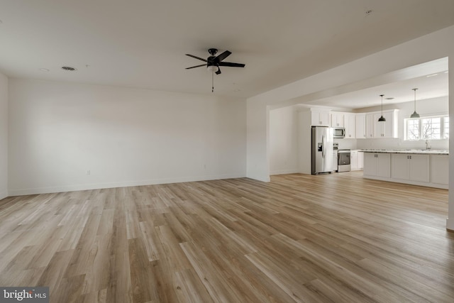 unfurnished living room with ceiling fan, sink, and light hardwood / wood-style flooring