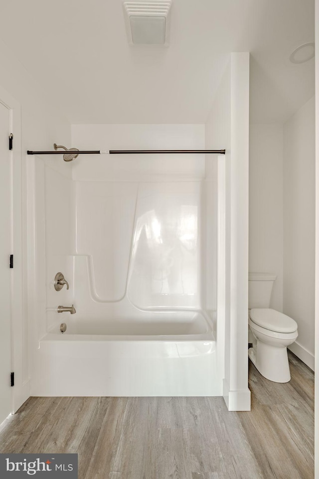 bathroom featuring toilet, shower / bath combination, and hardwood / wood-style floors