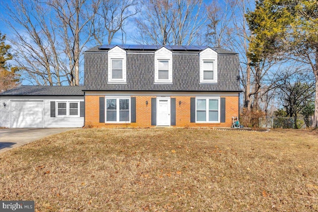 new england style home with a garage, a front yard, and solar panels