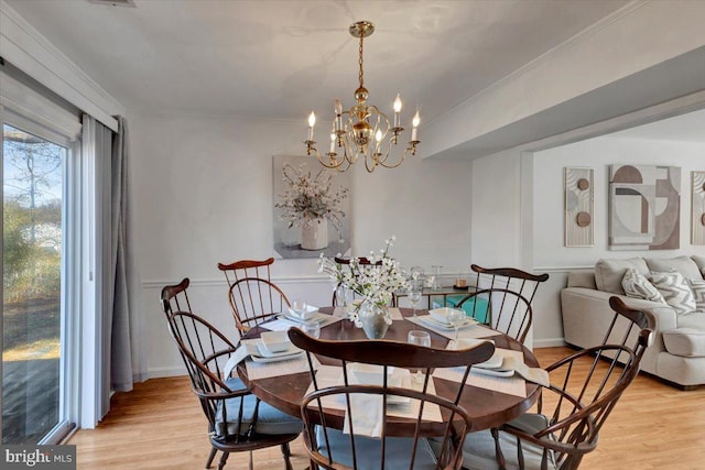 dining area featuring crown molding, a chandelier, and light hardwood / wood-style flooring