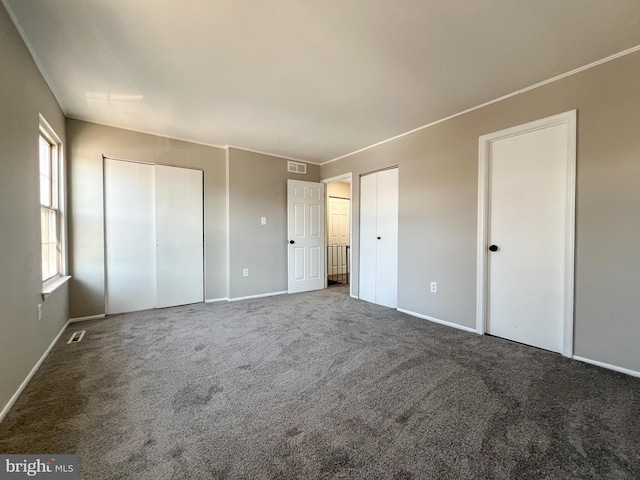 unfurnished bedroom featuring multiple closets and carpet floors