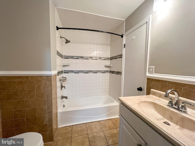 full bathroom featuring tiled shower / bath, tile walls, vanity, toilet, and tile patterned floors