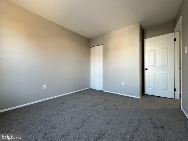 unfurnished bedroom featuring a closet and dark colored carpet