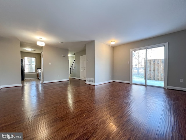 unfurnished living room featuring dark hardwood / wood-style flooring and a wealth of natural light