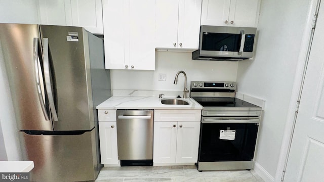 kitchen with light stone counters, stainless steel appliances, sink, and white cabinets