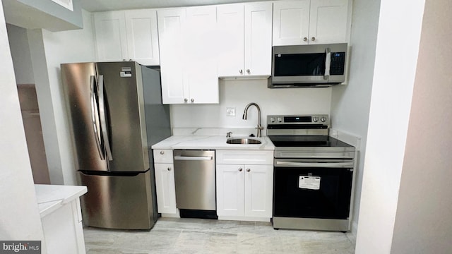 kitchen with light stone counters, sink, stainless steel appliances, and white cabinets