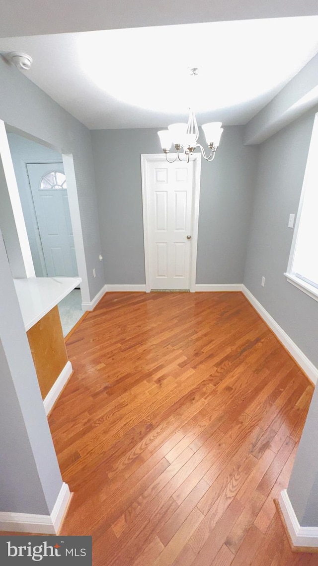 unfurnished dining area featuring a notable chandelier and light wood-type flooring