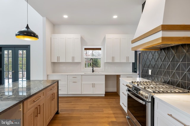 kitchen with white cabinetry, decorative light fixtures, stainless steel gas range, and custom exhaust hood