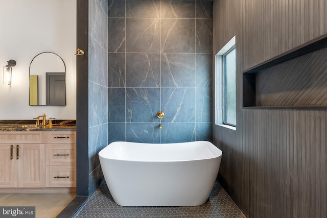 bathroom featuring tile patterned flooring, a bath, vanity, and tile walls