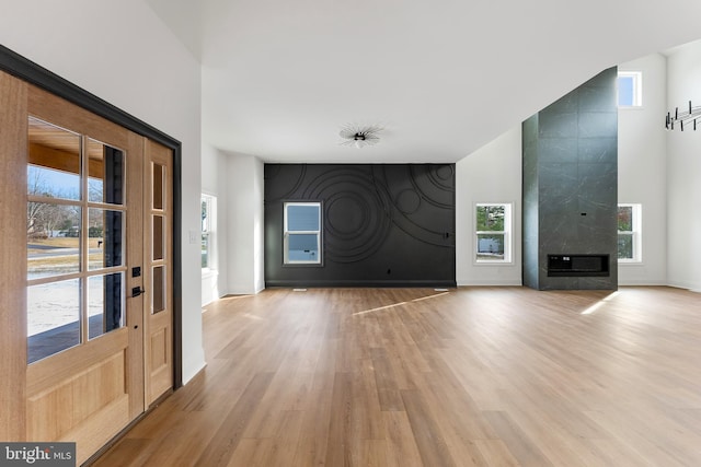 foyer with a high ceiling, light wood-type flooring, and a fireplace