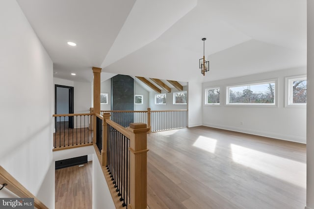 hall featuring light hardwood / wood-style floors, decorative columns, and vaulted ceiling with beams