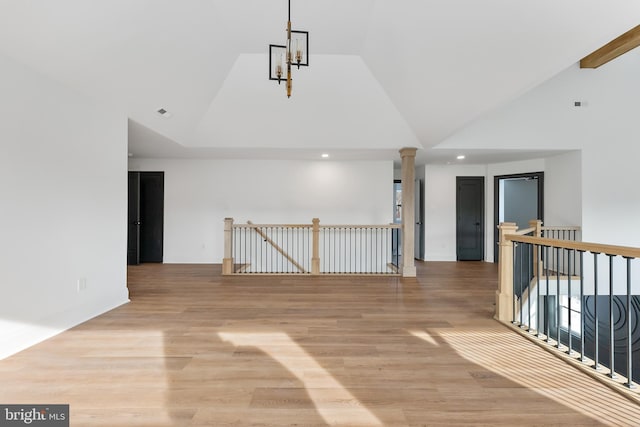 unfurnished room with light hardwood / wood-style flooring, high vaulted ceiling, and ornate columns