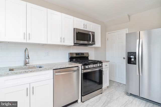 kitchen featuring appliances with stainless steel finishes, tasteful backsplash, sink, white cabinets, and light stone counters