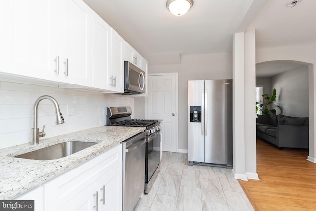 kitchen with sink, white cabinetry, stainless steel appliances, light stone counters, and tasteful backsplash