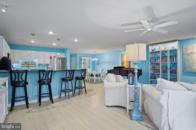 living room featuring ceiling fan, sink, and light hardwood / wood-style flooring