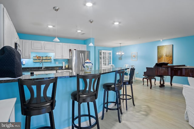 kitchen with sink, a breakfast bar area, appliances with stainless steel finishes, white cabinetry, and hanging light fixtures