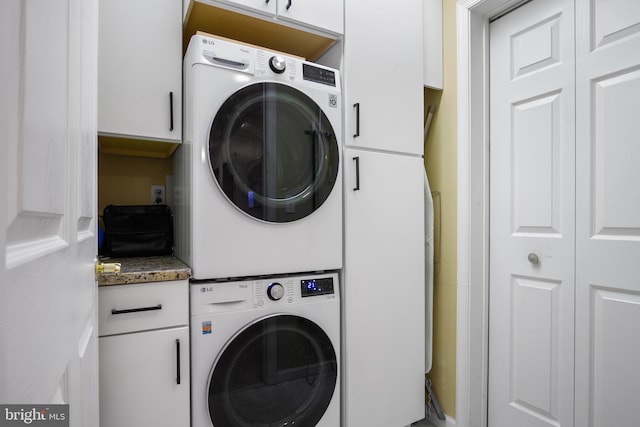 laundry area featuring cabinets and stacked washing maching and dryer