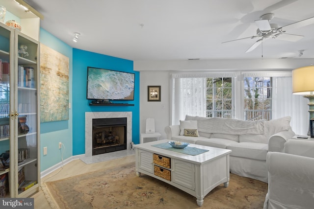 living room featuring a tiled fireplace and ceiling fan