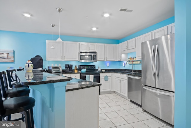 kitchen featuring appliances with stainless steel finishes, a breakfast bar, pendant lighting, white cabinetry, and sink