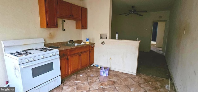 kitchen with sink, light tile patterned floors, white range with gas stovetop, and ceiling fan