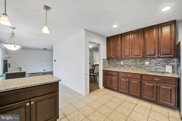 kitchen featuring light tile patterned floors, hanging light fixtures, decorative backsplash, a textured ceiling, and light stone countertops