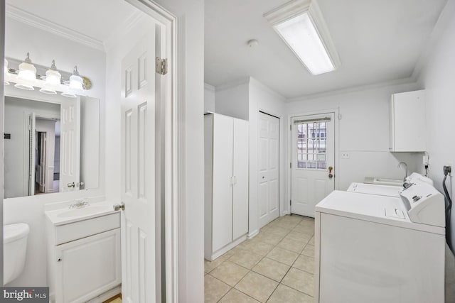 washroom featuring laundry area, light tile patterned floors, washer and clothes dryer, crown molding, and a sink