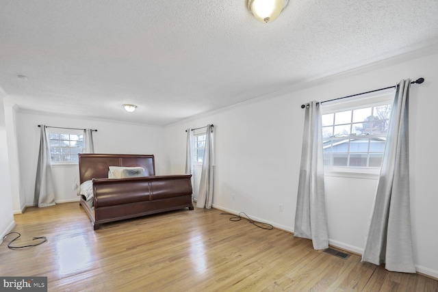 bedroom featuring baseboards, visible vents, light wood-style flooring, and a textured ceiling