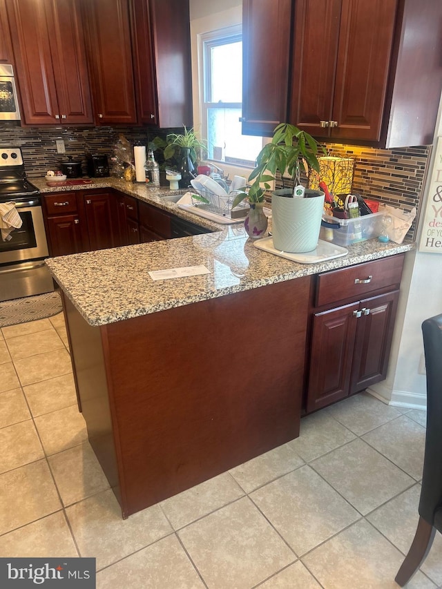 kitchen with light stone counters, light tile patterned flooring, stainless steel appliances, a peninsula, and decorative backsplash