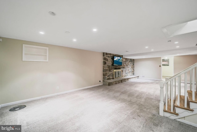 finished below grade area with carpet, recessed lighting, stairway, a stone fireplace, and baseboards