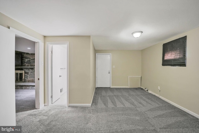 spare room with carpet, a fireplace, and baseboards