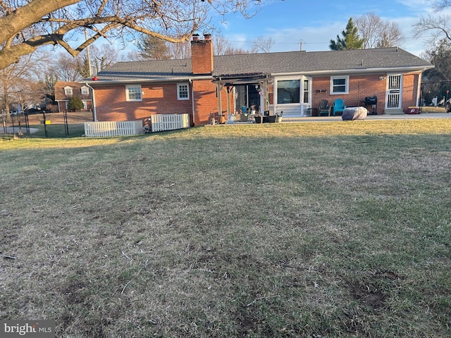 rear view of house with a patio area, brick siding, fence, and a chimney