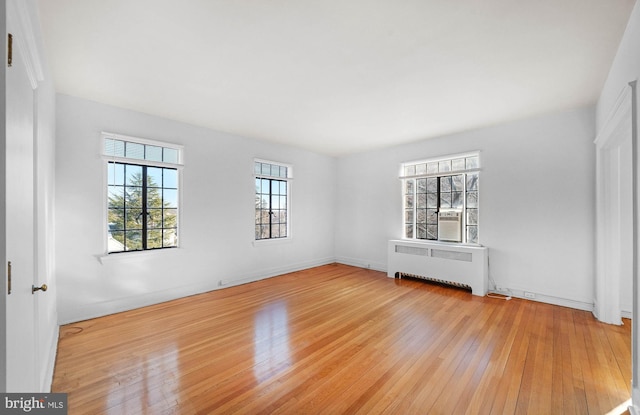 spare room featuring radiator and light hardwood / wood-style flooring