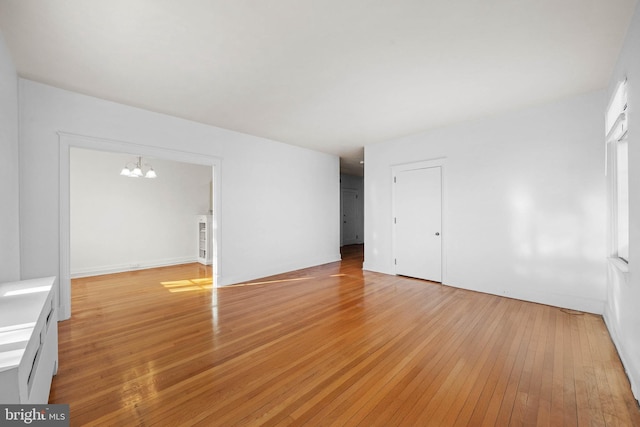 spare room with light hardwood / wood-style floors and a notable chandelier