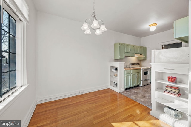 kitchen featuring white range with electric stovetop, sink, hanging light fixtures, hardwood / wood-style flooring, and green cabinets