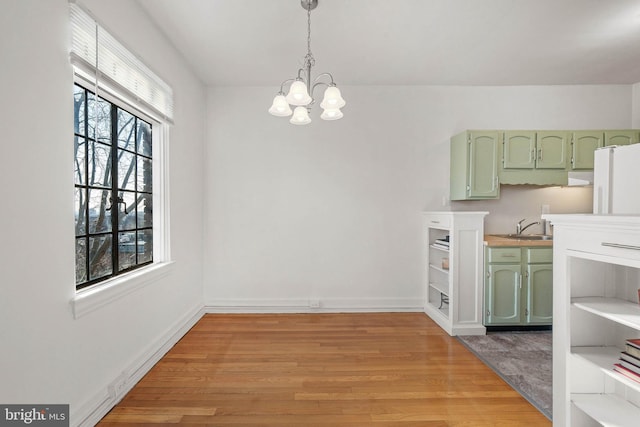 dining space featuring sink, a notable chandelier, and light hardwood / wood-style flooring