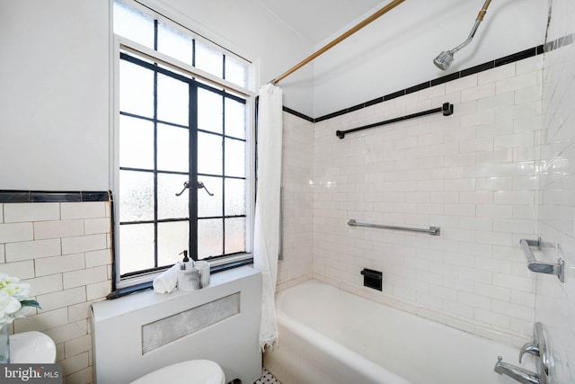 bathroom featuring shower / tub combo, toilet, and tile walls