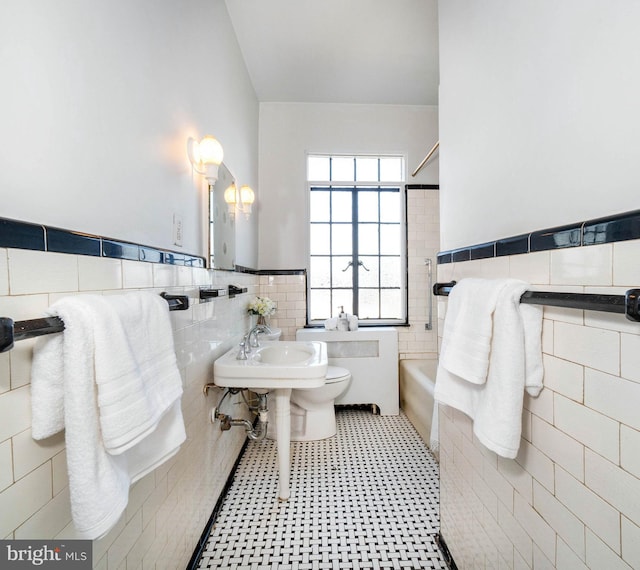 bathroom with toilet and tile walls